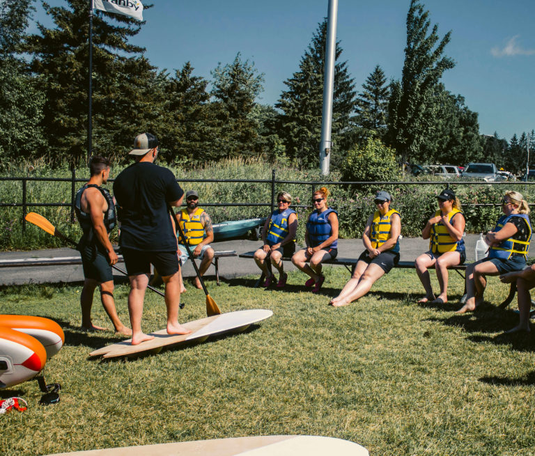 Les deux instructeurs de l'école de Paddleboard Wod Sup indiquent à leur groupe les instructions à suivre pour leur cours d'initiation au paddleboard.